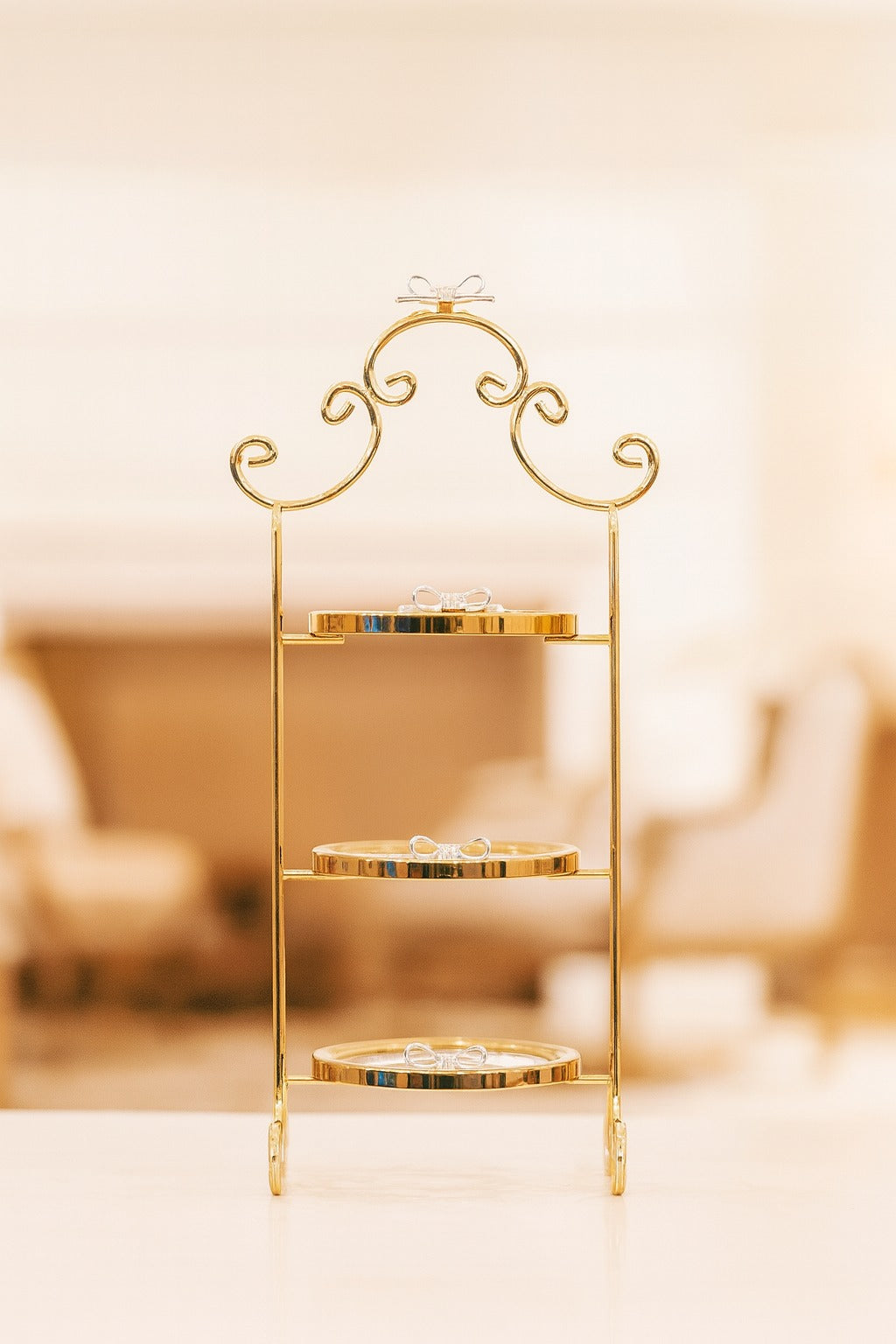 Izzhaar gold-toned 3-tier stand with delicate bow accents, perfect for sweets, gifting displays, or décor styling.